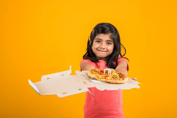 Portrait of cute indian girl holding an open box of pizza, excited asian girl opening pizza box showing smile on face, standing over yellow background