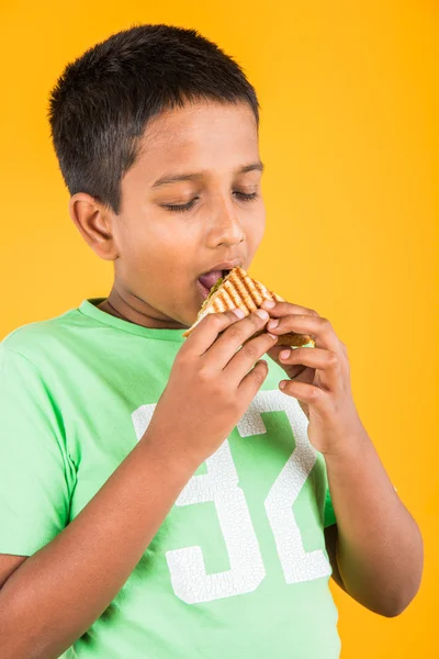 Indian kid eating sandwich, asian boy and sandwich, indian boy showing sandwich, cute african boy showing sandwich on yellow background