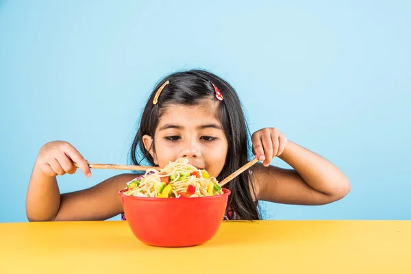 Happy Asian child eating delicious noodle, small indian girl eating noodles in red bowl