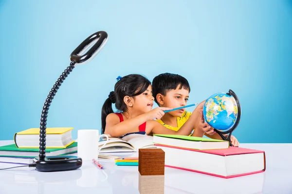 Indian boy and girl studying with globe on study table, asian kids studying, indian kids studying geography, kids doing homework or home work, two kids studying on table