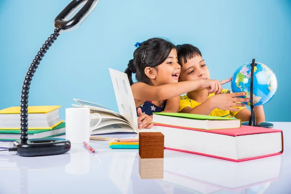 Indian boy and girl studying with globe on study table, asian kids studying, indian kids studying geography, kids doing homework or home work, two kids studying on table