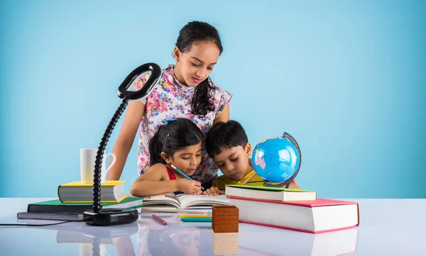 Three cute indian kids studying, smart asian girls and boy doing home work, indian siblings studying, indian small girl helping her brother and sister in doing homework