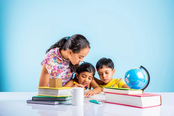 Three cute indian kids studying, smart asian girls and boy doing home work, indian siblings studying, indian small girl helping her brother and sister in doing homework