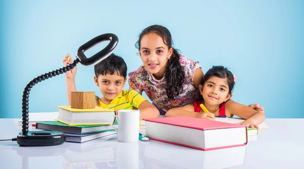 Three cute indian kids studying, smart asian girls and boy doing home work, indian siblings studying, indian small girl helping her brother and sister in doing homework