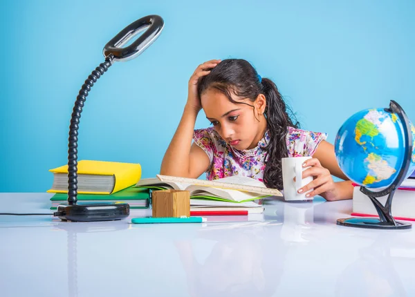 Education and home concept - stressed student girl with books, indian girl child tired of studying or doing homework, asian girl studying and stressed, with globe toy and coffee mug