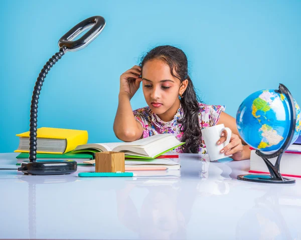 Education and home concept - stressed student girl with books, indian girl child tired of studying or doing homework, asian girl studying and stressed, with globe toy and coffee mug