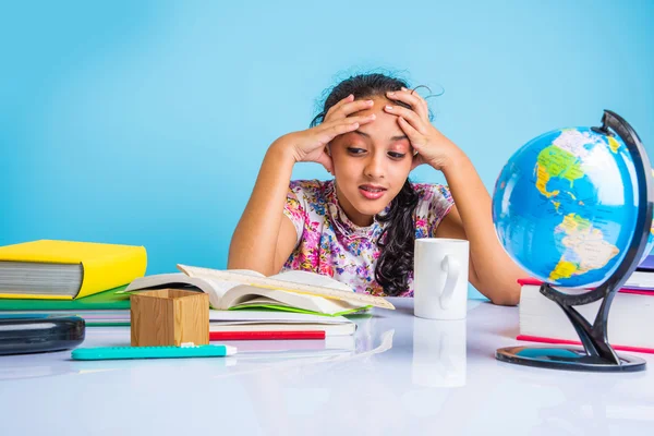 Education and home concept - stressed student girl with books, indian girl child tired of studying or doing homework, asian girl studying and stressed, with globe toy and coffee mug