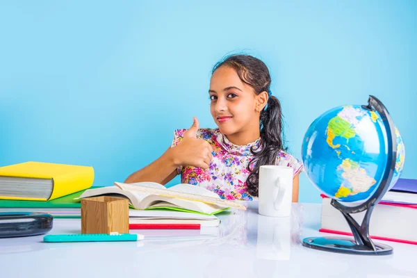 Education and home concept - stressed student girl with books, indian girl child tired of studying or doing homework, asian girl studying and stressed, with globe toy and coffee mug