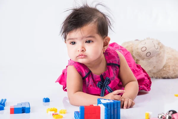 Indian baby playing with toys or blocks, asian infant playing with toys on white background, indian baby girl playing with toys, indian toddler playing with toys, indian baby girl lying on white floor