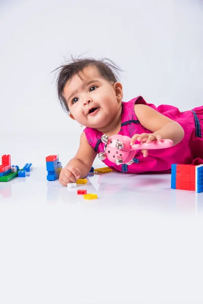 Indian baby playing with toys or blocks, asian infant playing with toys on white background, indian baby girl playing with toys, indian toddler playing with toys, indian baby girl lying on white floor