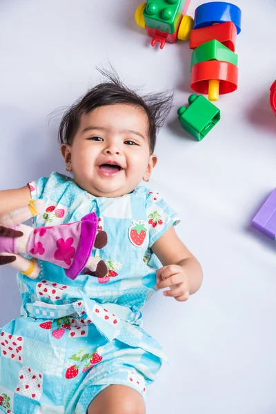Indian baby playing with toys or blocks, asian infant playing with toys on white background, indian baby girl playing with toys, indian toddler playing with toys, indian baby girl lying on white floor