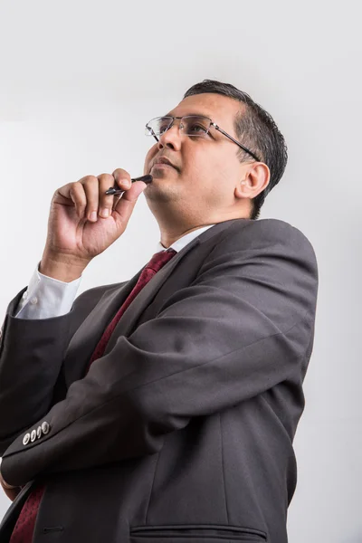 Indian businessman holding ball pen and thinking, indian businessman thinking, asian businessman holding pen while deep thinking, indian businessman solving problem, isolated over white background