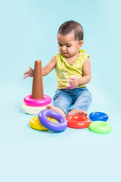 Baby Girl Stacking colorful Rings, Isolated over red, indian small girl playing with toy, asian baby girl playing with ring