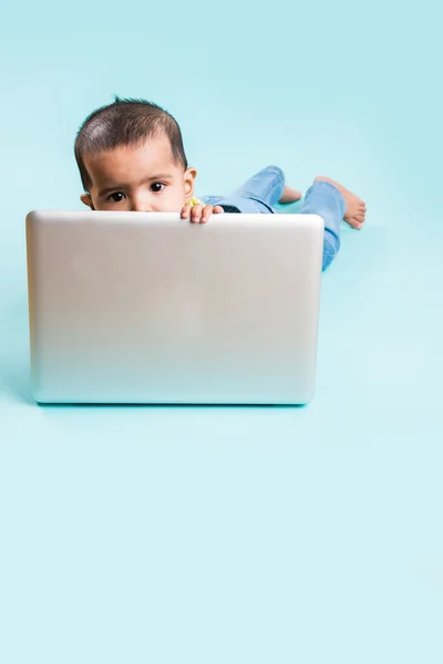 Baby sitting on the floor with a laptop, indian baby girl with laptop over blue background, indian baby girl playing with laptop, asian baby girl with laptop