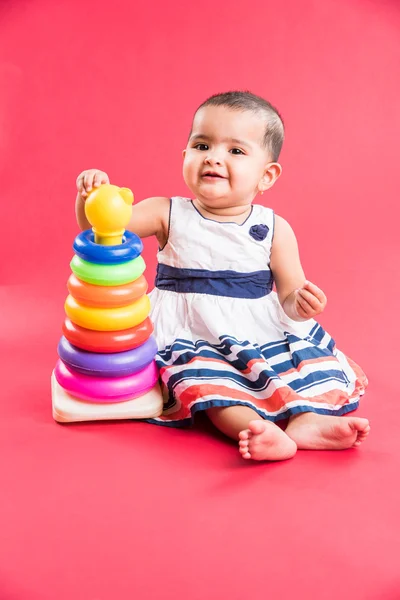 Baby Girl Stacking colorful Rings, Isolated over red, indian small girl playing with toy, asian baby girl playing with ring