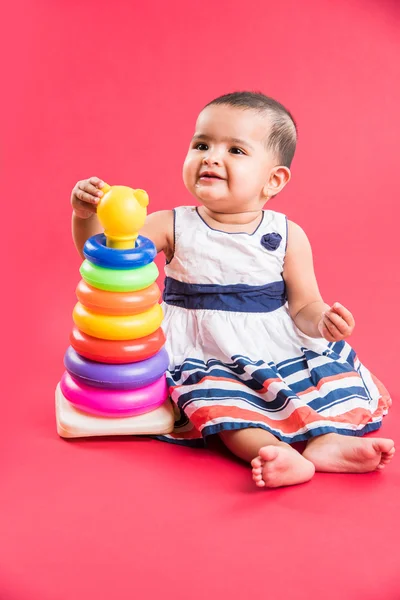 Baby Girl Stacking colorful Rings, Isolated over red, indian small girl playing with toy, asian baby girl playing with ring