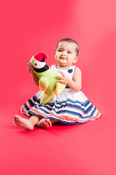 Indian toddler playing over red background, cute little indian baby girl playing with toys, indian baby girl playing, asian infant playing
