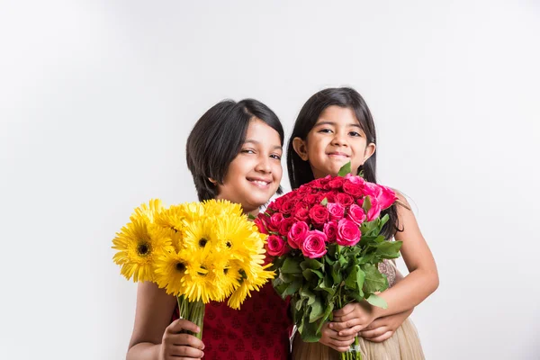 Two cute indian little girls holding flower bouquet, two small girls with gerbera and rose bouquet, isolated on white