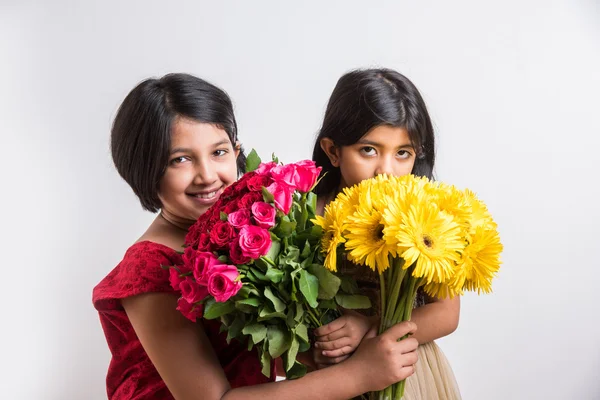 Two cute indian little girls holding flower bouquet, two small girls with gerbera and rose bouquet, isolated on white