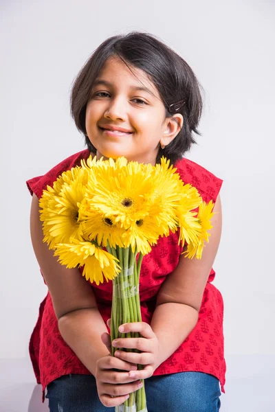 Indian small girl holding bouquet of yellow gerbera flowers, isolated over white background, indian girl and flowers, asian girk holding flowers