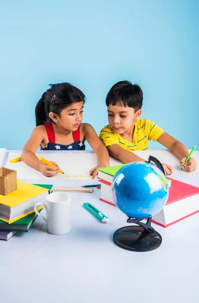 Indian boy and girl studying with globe on study table, asian kids studying, indian kids studying geography, kids doing homework or home work, two kids studying on table