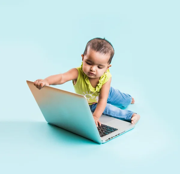 Baby sitting on the floor with a laptop, indian baby girl with laptop over blue background, indian baby girl playing with laptop, asian baby girl with laptop