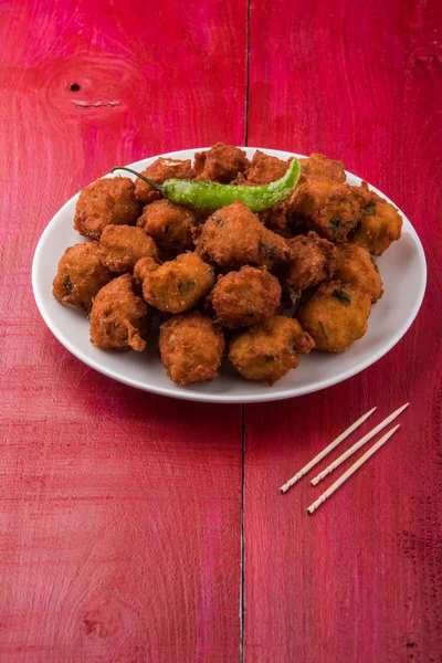 Delicious Tasty and Yummy Indian Moong Dal vada or moong dal pakoda or moong vade or Pakora (Fritter) with fried green chilli, red and green hot sauce.