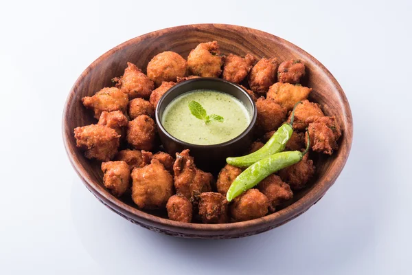 Delicious Tasty and Yummy Indian Moong Dal vada or moong dal pakoda or moong vade or Pakora (Fritter) with fried green chilli, red and green hot sauce.