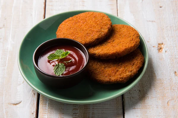Indian chat item aloo or aalu tikki or tikiya or fried potato cake also known as ragda patties served with tomato ketchup, selective focus