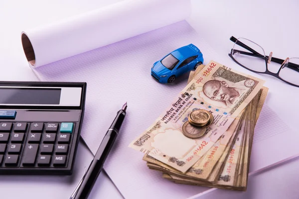 Buying home and car concept, indian currency notes, model home, keys, toy car and calculator, isolated