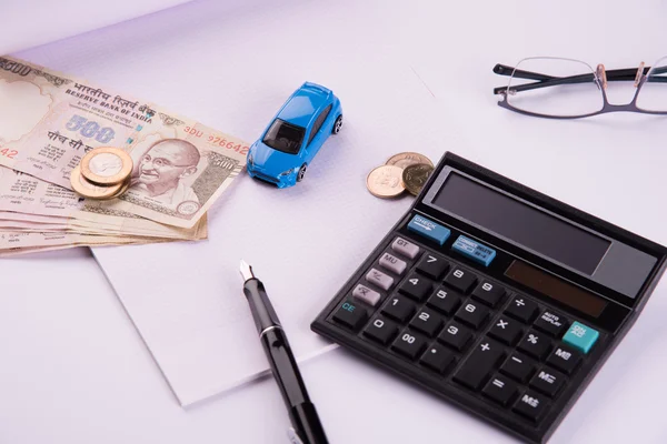 Buying home and car concept, indian currency notes, model home, keys, toy car and calculator, isolated