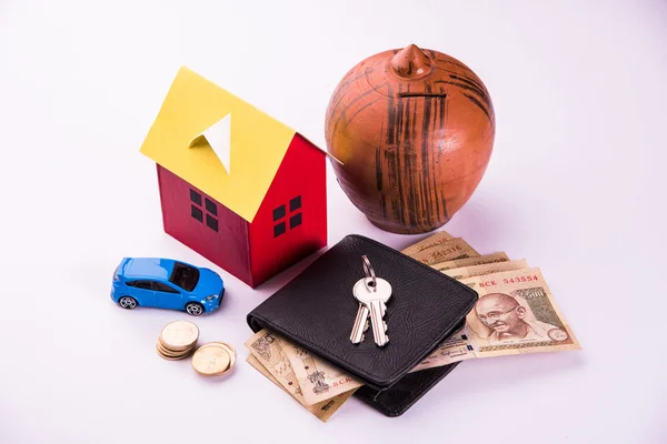 Buying home and car concept, indian currency notes, model home, keys, toy car and calculator, isolated