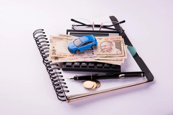 Buying home and car concept, indian currency notes, model home, keys, toy car and calculator, isolated