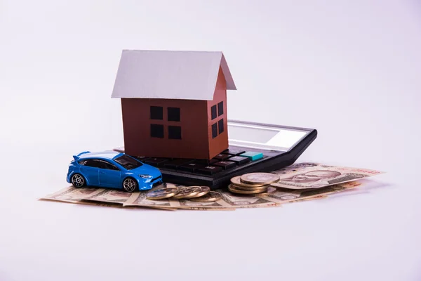 Buying home and car concept, indian currency notes, model home, keys, toy car and calculator, isolated