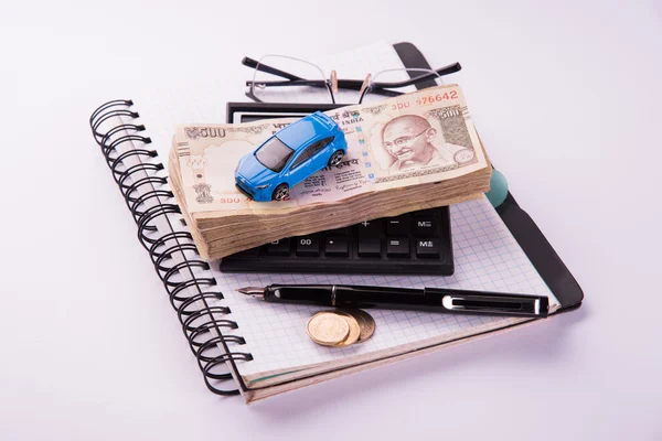 Buying home and car concept, indian currency notes, model home, keys, toy car and calculator, isolated