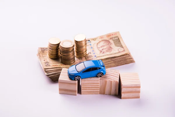 Buying home and car concept, indian currency notes, model home, keys, toy car and calculator, isolated