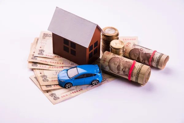 Buying home and car concept, indian currency notes, model home, keys, toy car and calculator, isolated