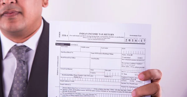 Indian businessman showing indian income tax return form or ITR-4 form or form no. 16 of income tax department of india, selective focus