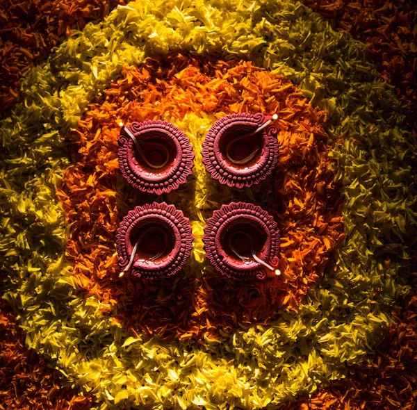 Traditional diya or oil lamp lit on colorful rangoli made up of flower petal, on the festival of lights called diwali or deepawali, selective focus