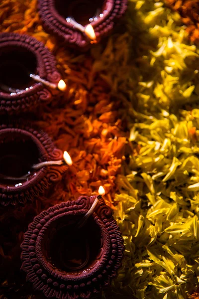 Traditional diya or oil lamp lit on colorful rangoli made up of flower petal, on the festival of lights called diwali or deepawali, selective focus