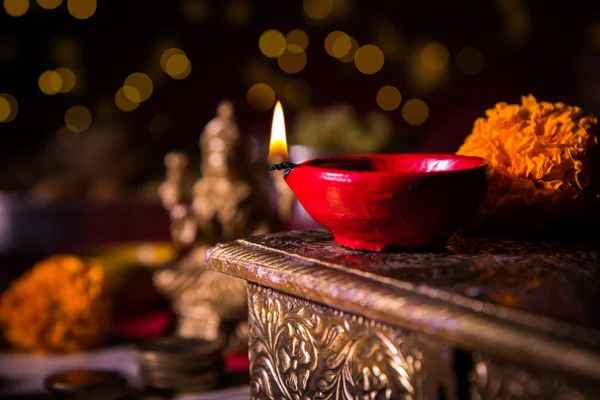 Oil lamp or diya with crackers, sweet or mithai, dry fruits, indian currency notes, marigold flower and statue of Goddess Laxmi or lakshmi on diwali night