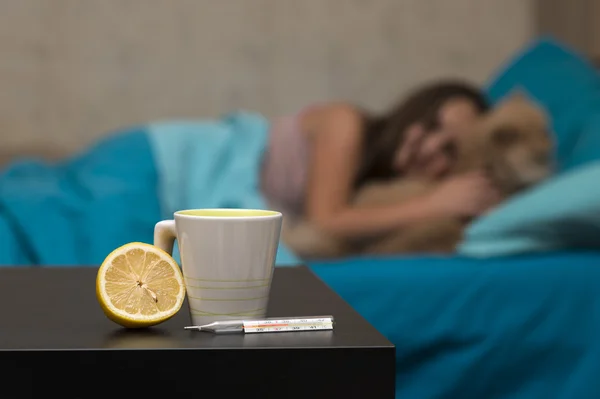 Tea with lemon on a background of ailing girl in bed
