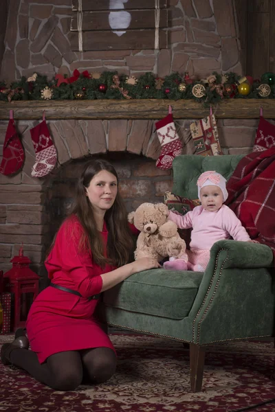 Christmas party. mother and daughter in a chair by the fireplace and Christmas tree