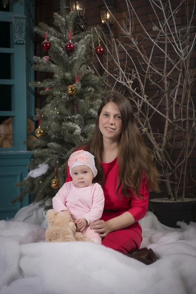 Christmas party. mother and daughter in a chair by the fireplace and Christmas tree