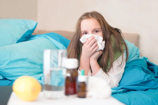 A sick baby lying in bed with a thermometer