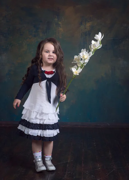 Funny little girl in a white dress with a flower in the hands