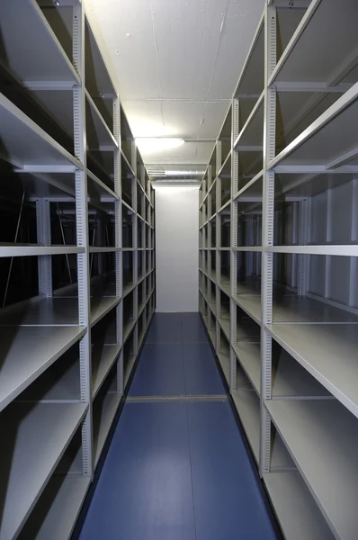 An empty storage unit with shelving on both walls -