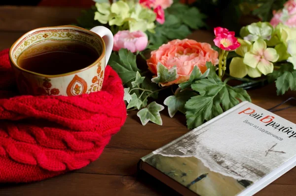 Cup of tea, book and artificial flowers