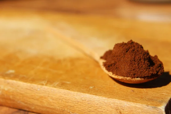 Wooden scoop with ground coffee on a brown wooden background