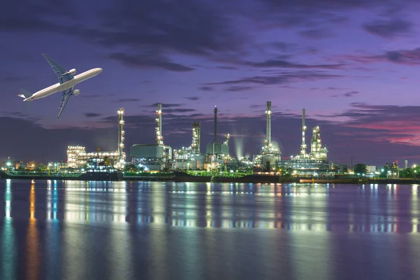 Tanker Oil refinery plant at twilight with airplane flying over